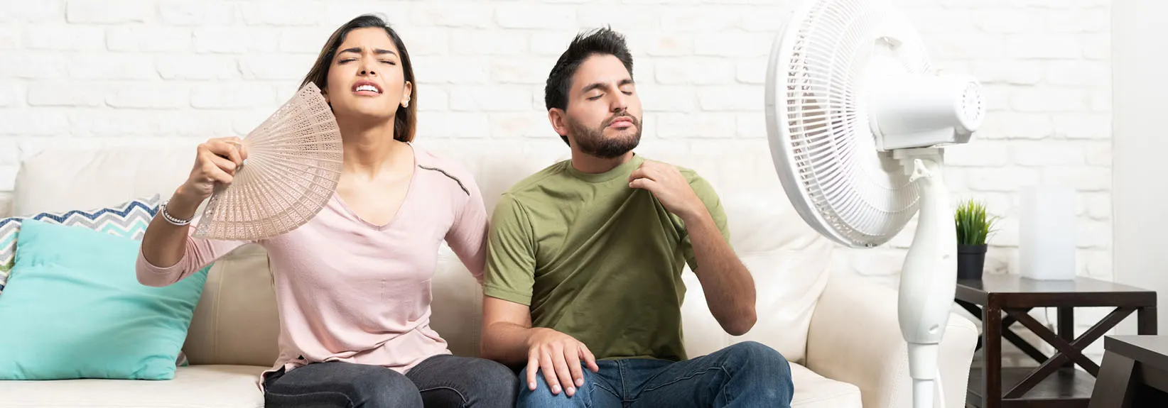 Couple Sitting In Front Of Fan During Hot Weather